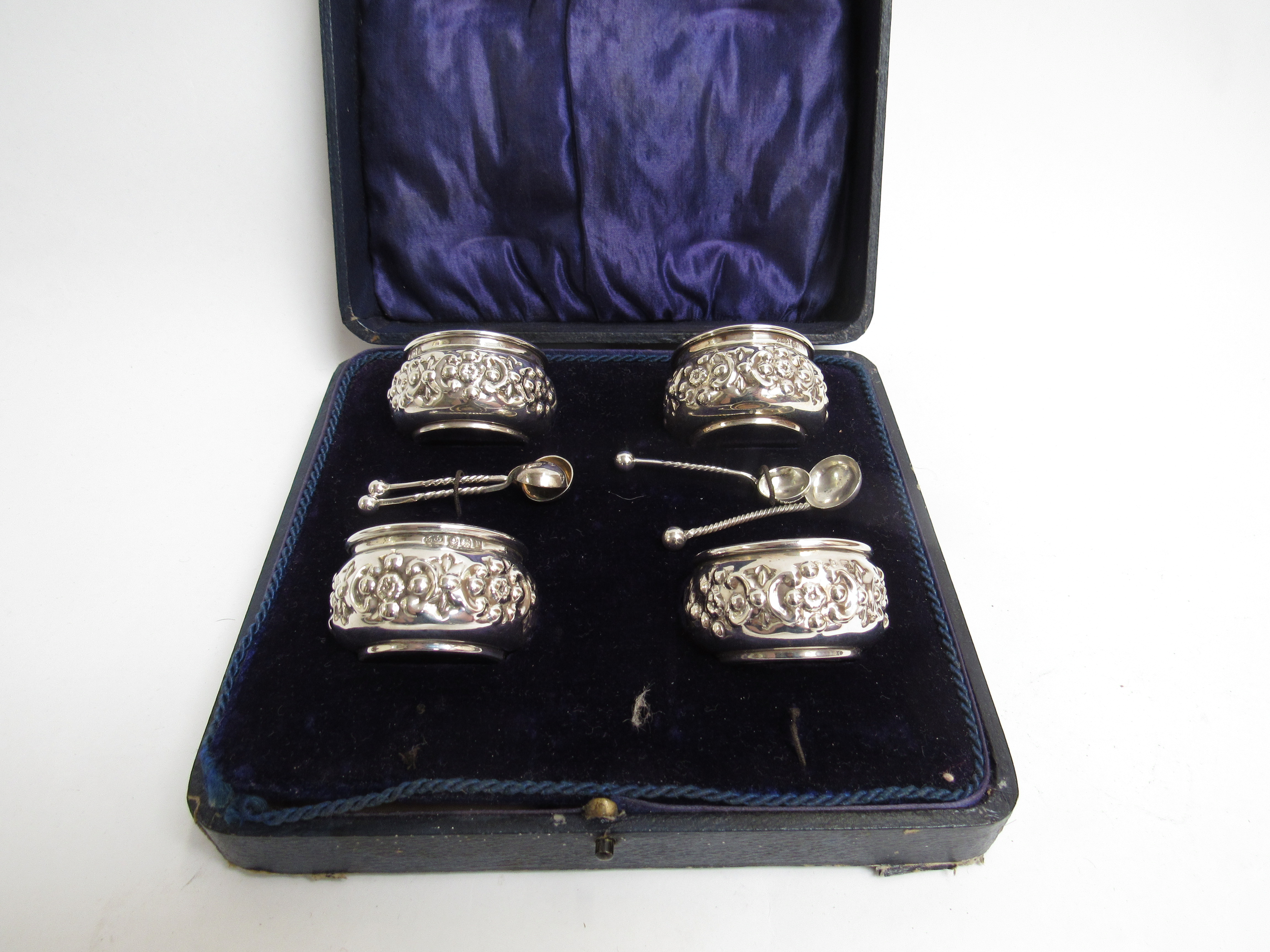 A Joseph Gloster Ltd silver set of four table salts with embossed floral design with spoons, cased,