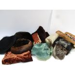 A box containing various hats, velvet and fur, straw and sheepskin, fox fur stole,
