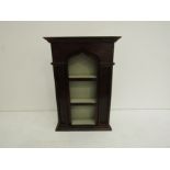 A 19th century set of oak hanging shelves in the Gothic taste with an arched top over a painted