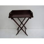 A 19th century mahogany butler's tray on folding stand with turned legs.