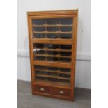 A large Edwardian light oak haberdashery shop unit, comprising three glazed up-and-over doors,