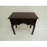 A George III mahogany lowboy with three frieze drawers and shaped apron.