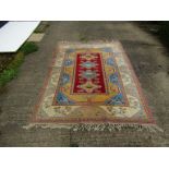 A hand woven Caucus rug with light blue colouring and tasselled ends,