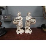 A pair of German porcelain figures holding baskets. Late 19th Century. 18.