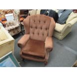 A brown button back wingback armchair