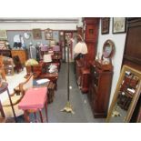 A Victorian brass standard lamp with crooked and scrolled arm joining a shade,