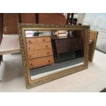 A gilt modern wall mirror of rectangular form,