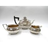 A Walker & Hall silver three piece tea set, stirrup form handles and fluted design,