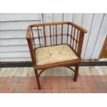 An early 20th Century oak cube chair with spindle and knob support on a crinoline stretcher