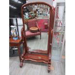 A Victorian flame mahogany cheval mirror with arched top, serpentine base,