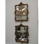 A pair of ornate gilt gesso framed wall mirrors with bevel glass