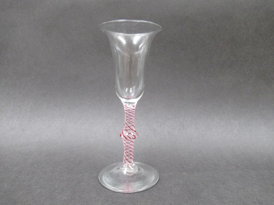 An 18th Century wine glass with bell shaped bowl on a knopped opaque white and red spiral twist