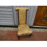 A Victorian walnut prie-dieu chair with floral gold upholstery and scroll carved supports