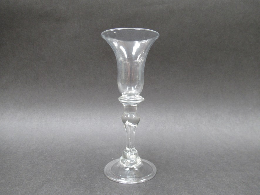 An early 18th Century wine glass with bell - shaped bowl set on a compressed three ring collar knop