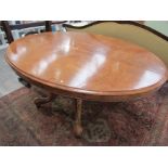 A Victorian walnut oval loo table, tilt top over quatreform carved supports to castors,