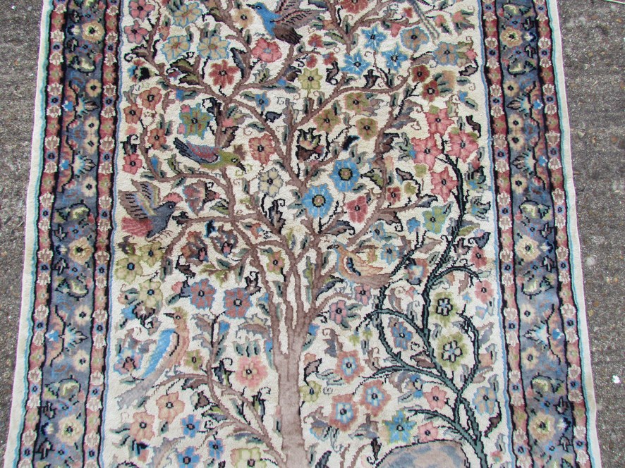 A modern hand made rug central field decorated with deer, tree blossoming plants and birds,
