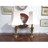 A pair of brass effect table lamps with cream shades,
