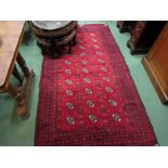 An Eastern red ground wool rug, central field of three rows of guls, multiple geometric borders,