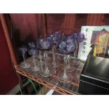 Twelve amethyst cut glass hock/sherry glasses with faceted stems and star cut bases