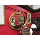 A gilt framed oval wall mirror with shaped frame,