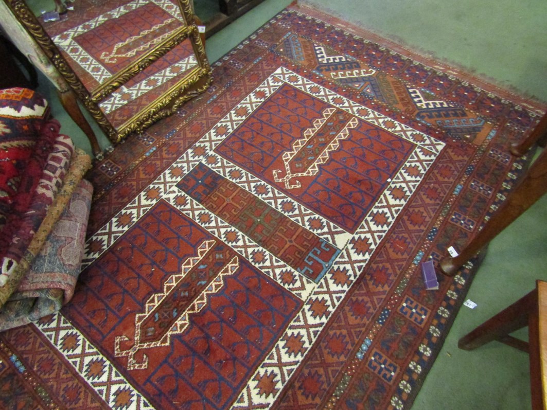 A red ground Eastern rug with multiple borders and tasselled end,