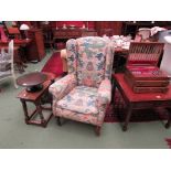 An Edwardian wingback armchair on turned front legs on castor feet decorated with Oriental design