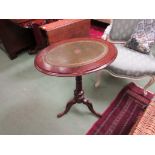 A Victorian walnut oval top wine table with gilt tooled leather inset on a turned column and tripod