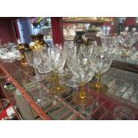 A collection of 1930's drinking glasses with pale amber stems plus other earlier etched examples