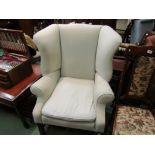 A Georgian style wingback armchair the scroll arms over mahogany square legs and stretchers