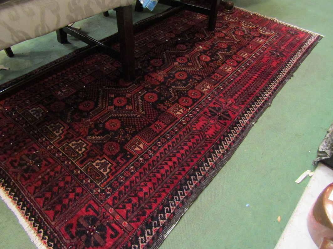 An Eastern black and red ground wool rug, central geometric field with multiple borders,