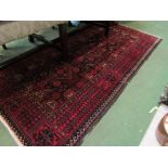 An Eastern black and red ground wool rug, central geometric field with multiple borders,