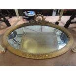 A 19th Century style gilt wood oval wall mirror with ribbon and foliate crest,