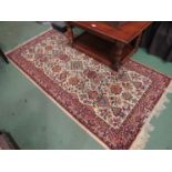 A Teheran machine woven beige and red ground rug with tasselled ends,
