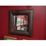 A square raised form pierced metal Eastern influence bevel edged wall mirror,