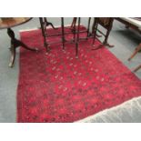 A red and black patterned rug with tasselled ends,