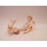 A pair of German porcelain figures of cherubs, one rolling over,