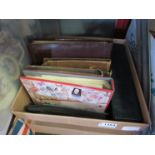 A box containing collectibles including cigarette cards, tins, stamp album,