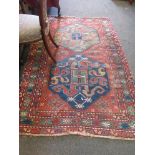 An Eastern wool rug, red ground, multiple borders with blue and green central panels and motifs,