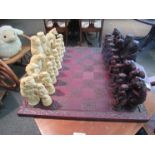 A chess set with resin animal form pieces and carved wooden board