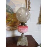 A Victorian oil lamp with acid etched shade, pink reservoir and pierced cast metal base,