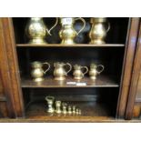 A set of seven graduating brass weights and seven gun metal measuring jugs