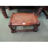 An Edwardian bergère stool, the caned seat on turned legs joined by barley-twist stretchers,