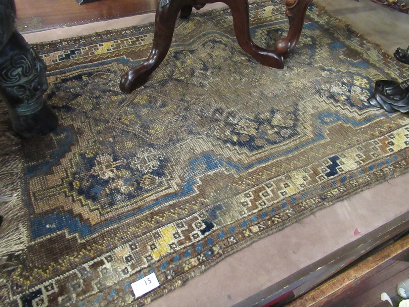 An Eastern blue and brown ground rug, heavily worn,