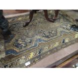 An Eastern blue and brown ground rug, heavily worn,