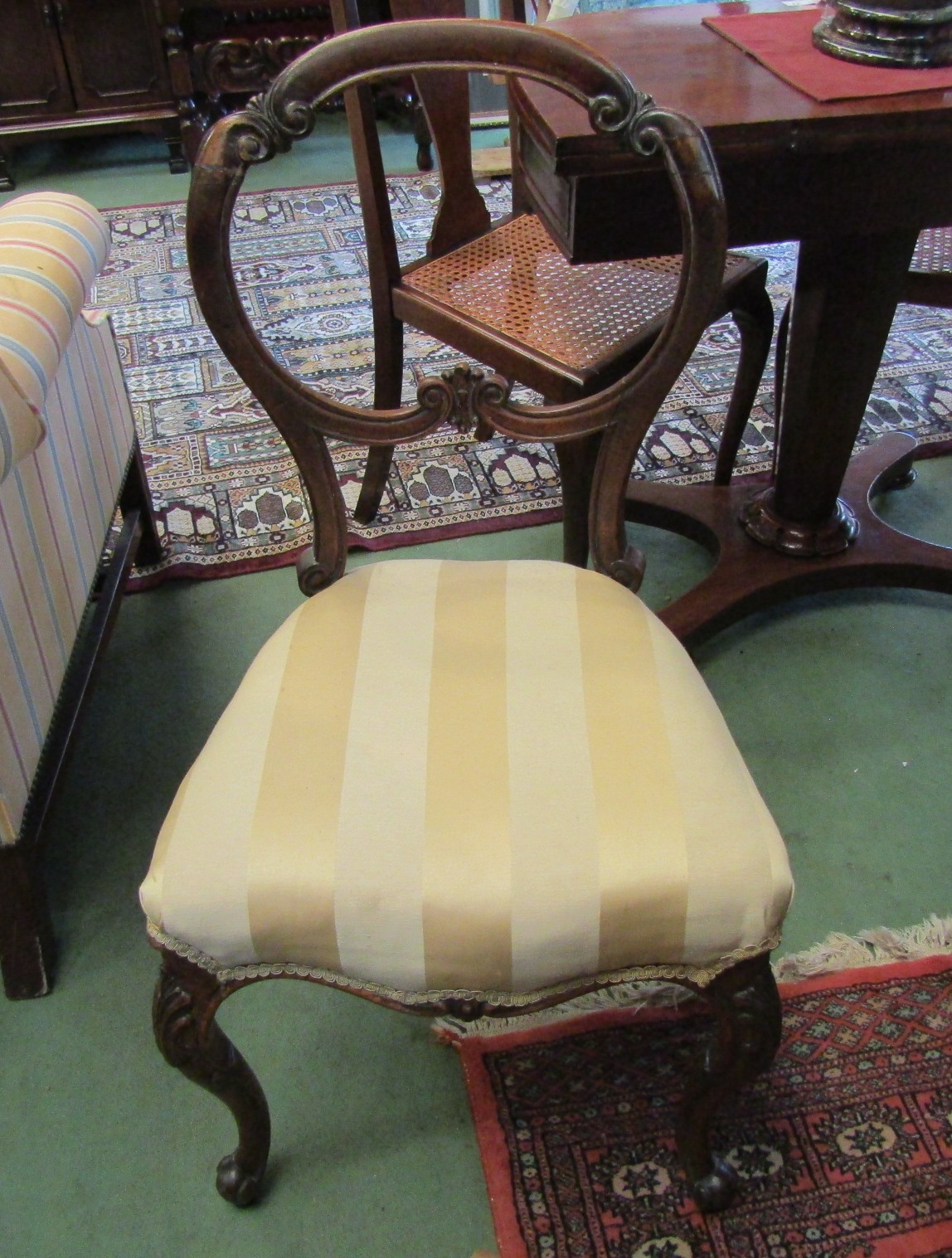 A pair of Victorian walnut balloon back chairs with carved decoration on scroll foot cabriole fore