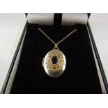 A 9ct gold locket on chain with sapphire centre hung on a 9ct gold chain,