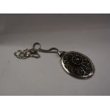 A large silver oval pendant with floral design on chain