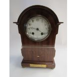 A mahogany mantel clock with brass plaque and inlaid decoration with key,