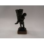 A bronze figure of boy holding an oversized boot,