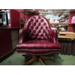 A Georgian style red leather button back library swivel desk armchair with brass stud decoration
